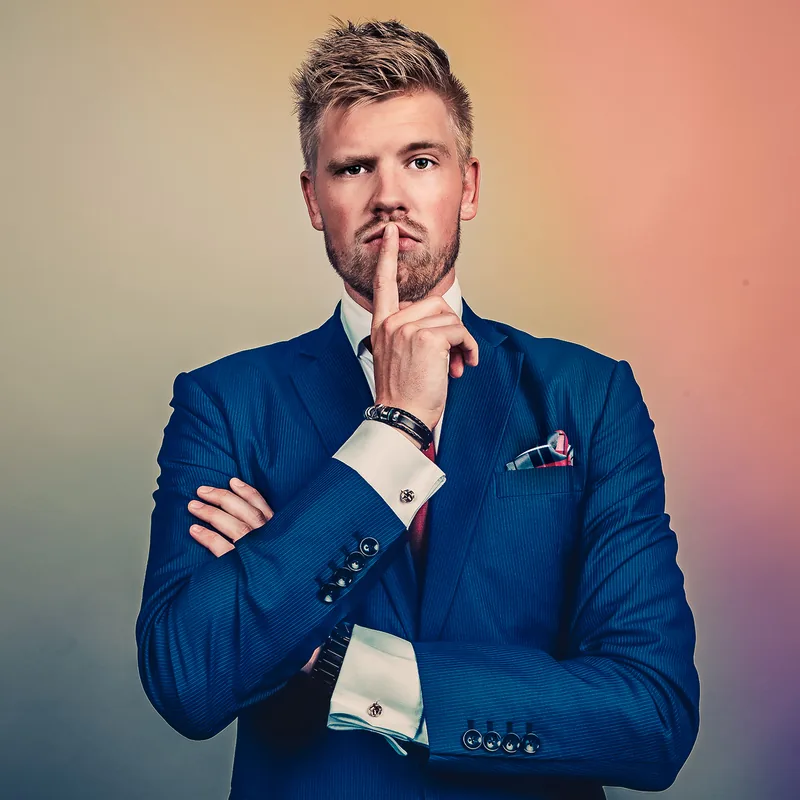 Bart Grootveld in een blauw pak, met een vinger voor zijn mond